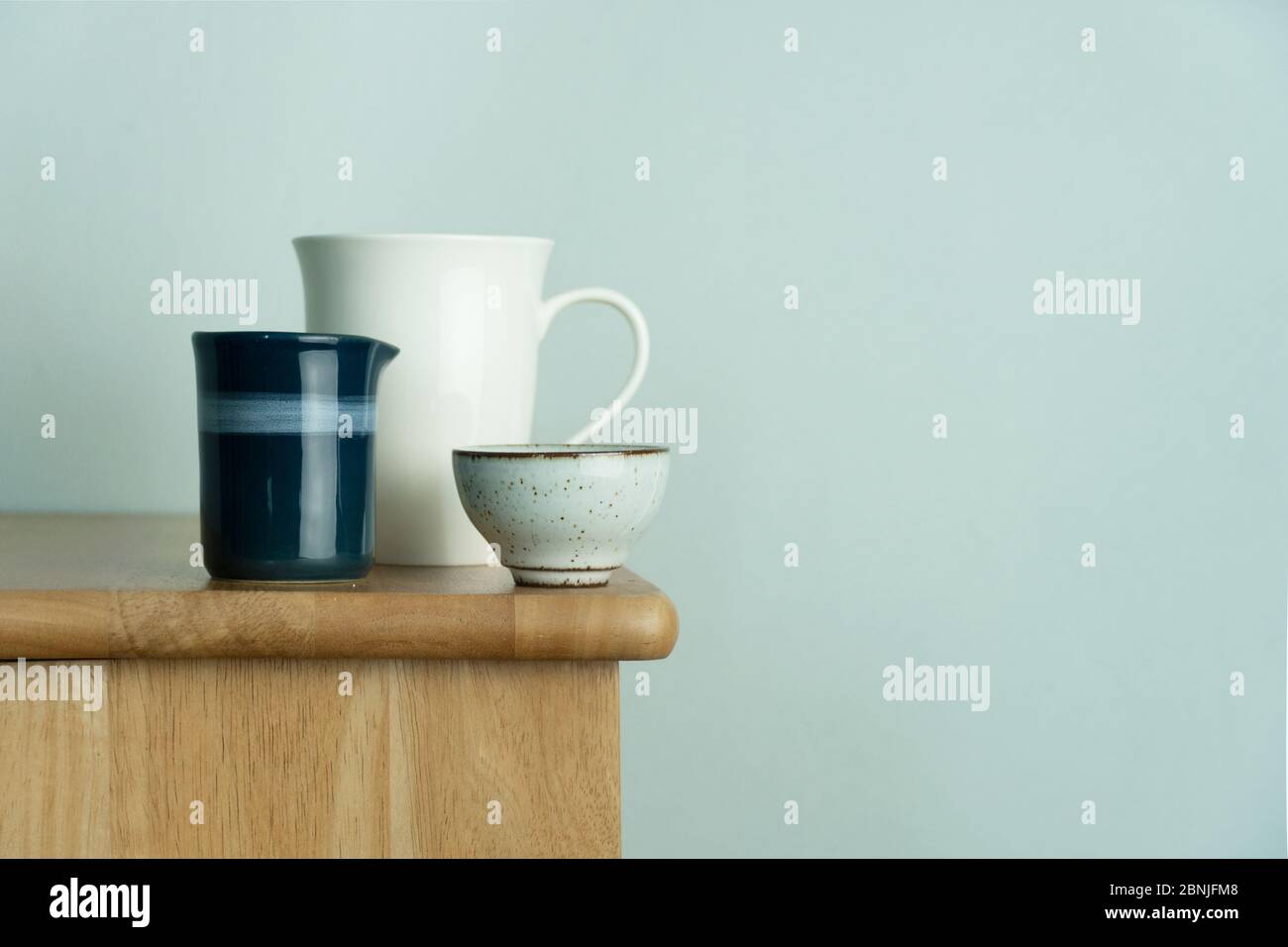 tazza bianca in ceramica e tazza da tè su tavolo in legno naturale con parete in cemento blu vintage per bevande alimentari e sfondo interno Foto Stock