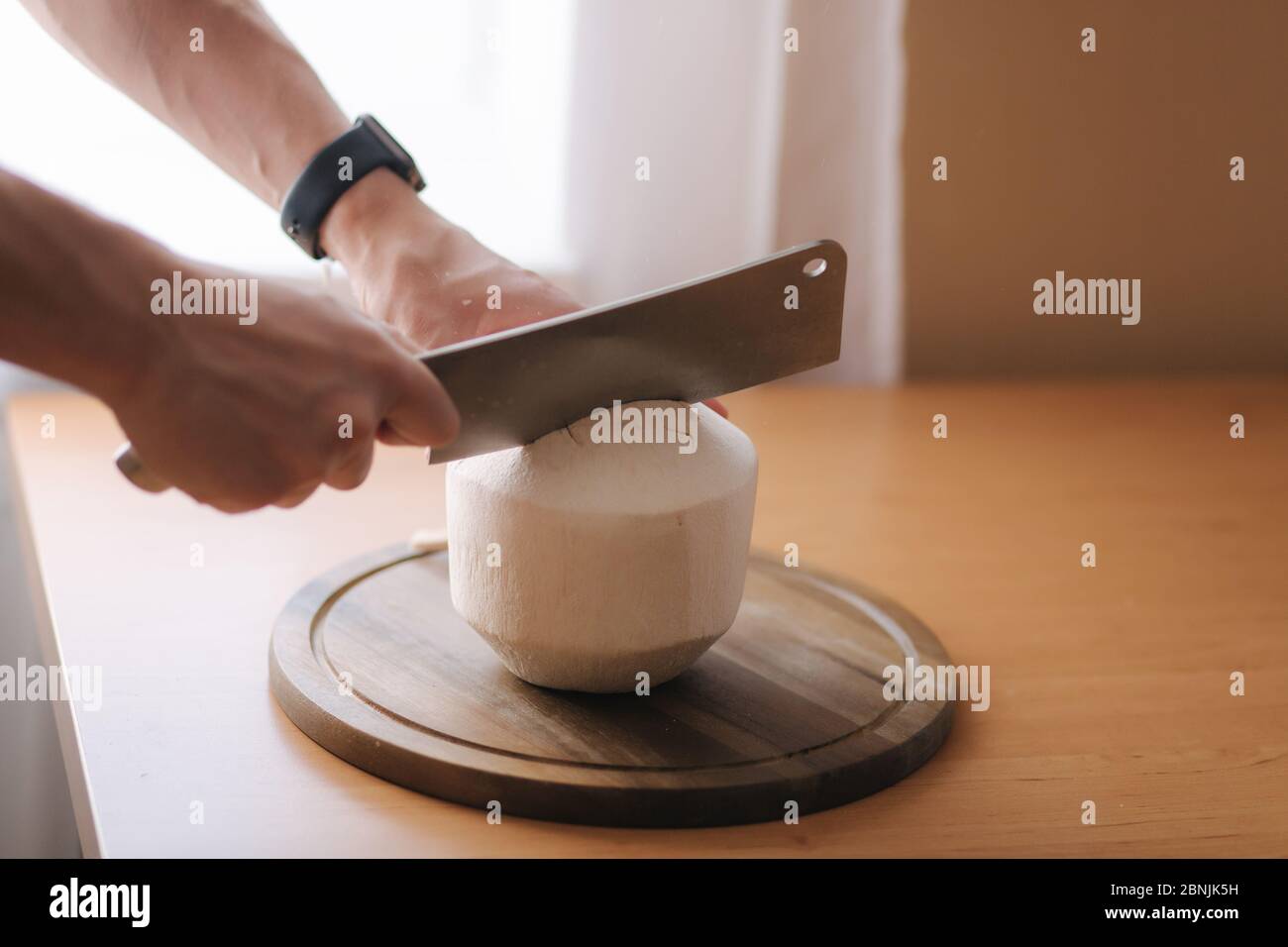 Uomo usa il coltello machete per aprire il cocco a casa Foto Stock