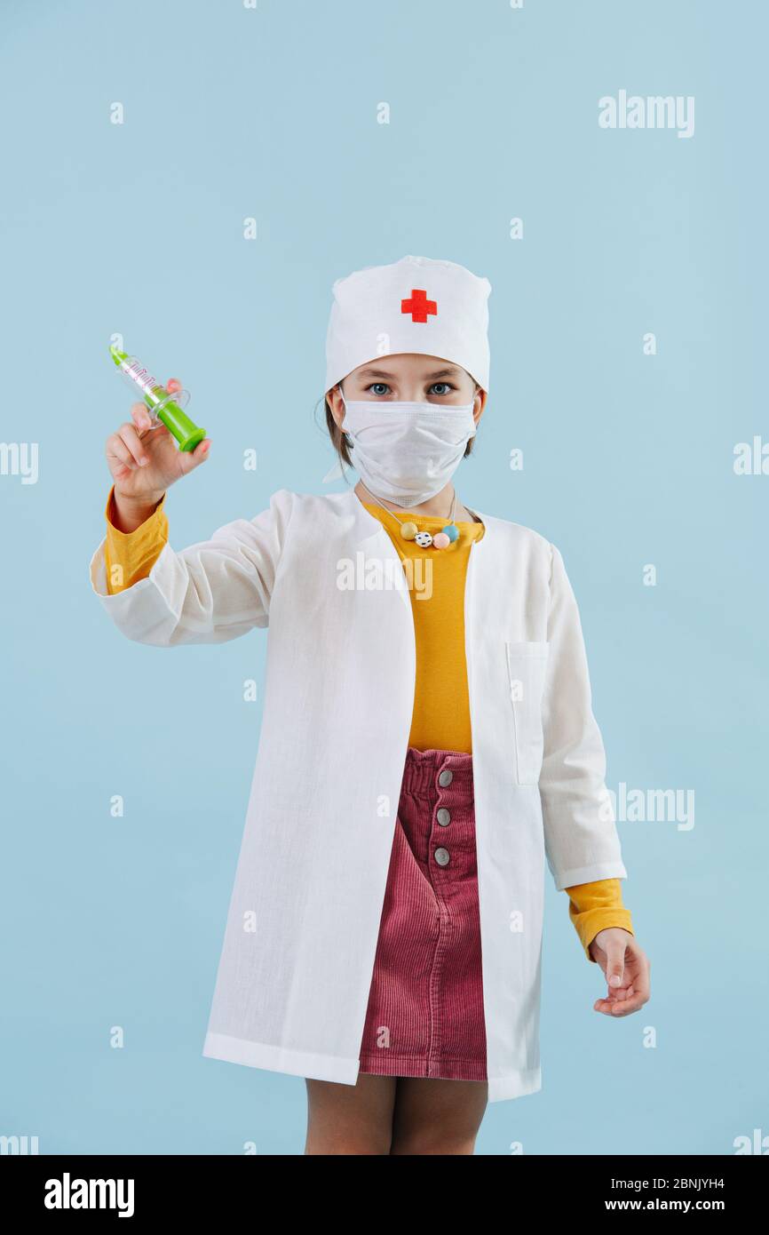 Bambina che gioca un medico su sfondo blu. Pandemia ispirata Foto Stock
