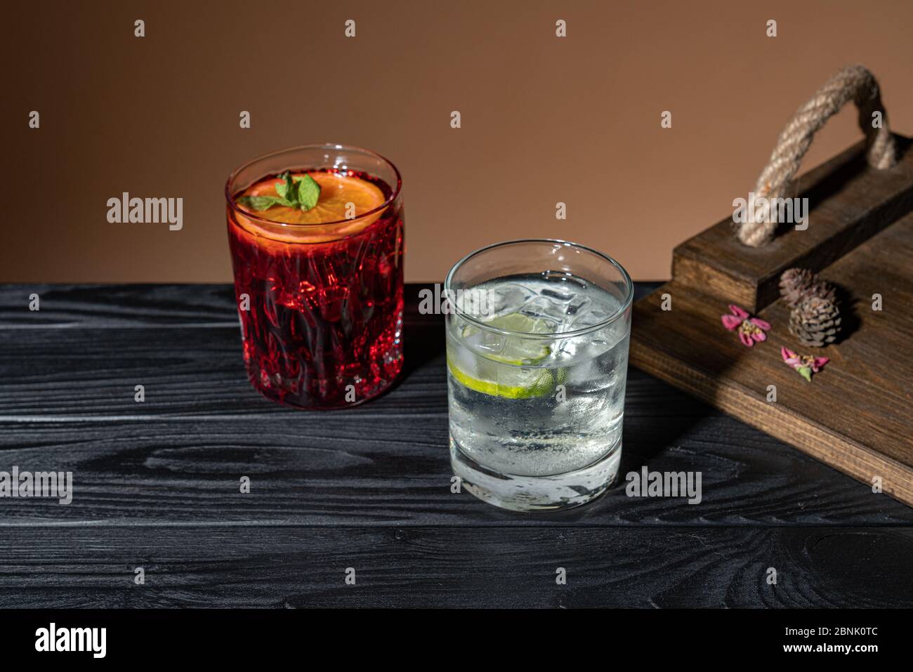 Due cocktail su un tavolo di legno vicino ad un vassoio, un Negroni altro Caipirinha, bevanda alcolica tradizionale brasiliana, bevanda tipica a base di zucchero, limone Foto Stock