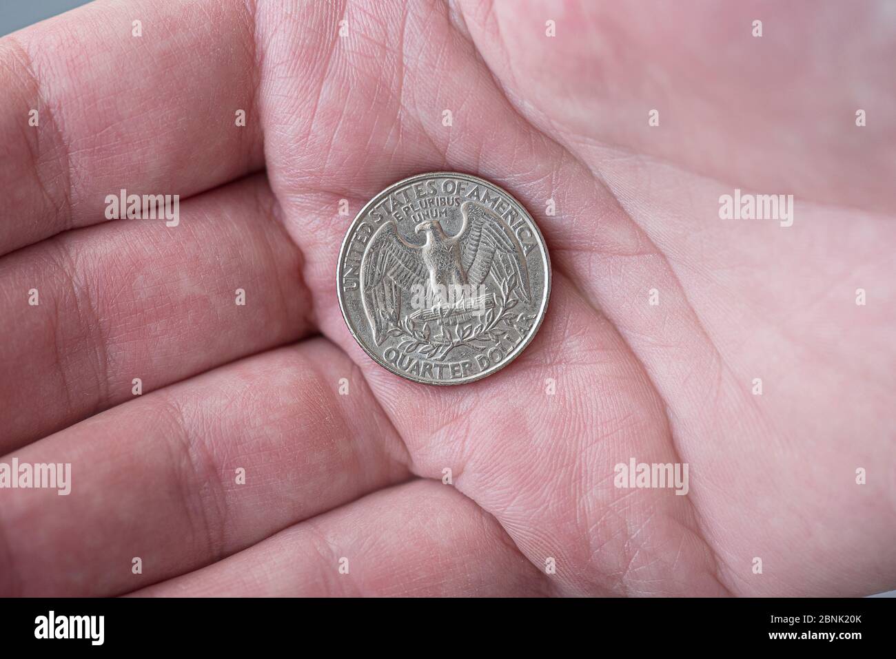 Un uomo che tiene una moneta da un quarto di dollaro americano d'argento, 25 centesimi, USA Foto Stock