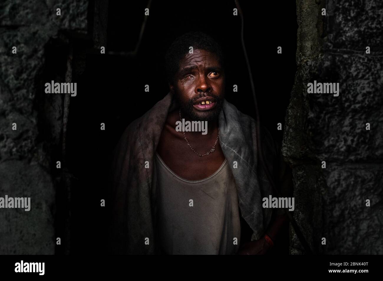 Un uomo colombiano parzialmente cieco si stilla fuori dal buio interno di un cavalcavia di cemento nella periferia di Bogotá, Colombia. Foto Stock