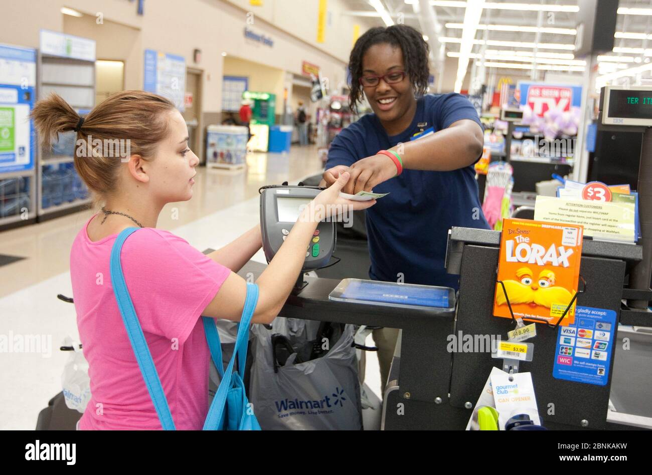 San Marcos Texas USA, 2012: Sorridente ragazza afro-americana dà cambio di denaro a una giovane donna bianca in un Wal-Mart Supercenter. ©Marjorie Kamys Cotera/Daemmrich Photos Foto Stock
