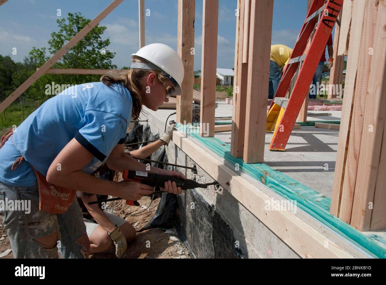 Austin Texas USA, 2012: Volontario femminile che indossa occhiali di sicurezza e elmetto aiuta a costruire una casa a prezzi accessibili con Habitat for Humanity. Habitat for Humanity finanzia e costruisce casa che i residenti a basso reddito potrebbero permettersi attraverso prestiti a tasso zero. ©Marjorie Kamys Cotera /Daemmrich Photography Foto Stock