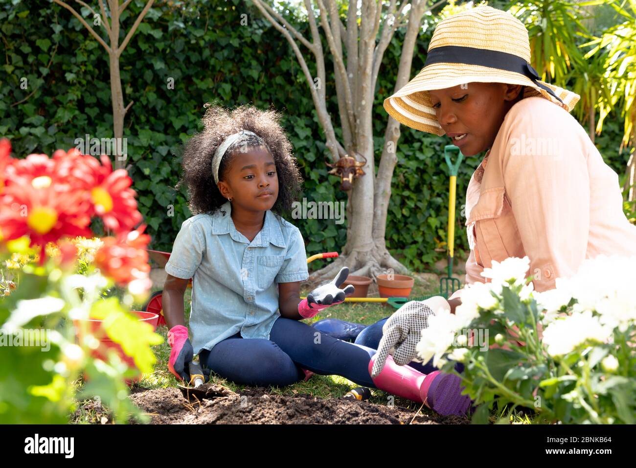 Ragazza afroamericana e sua nonna che piantano fiori nel loro giardino Foto Stock