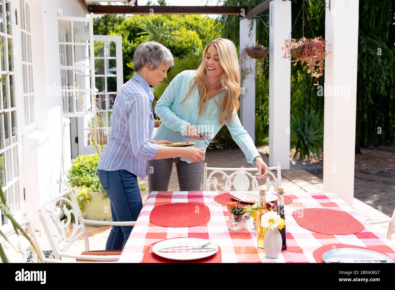 Due donne caucasiche preparano un pranzo in giardino Foto Stock