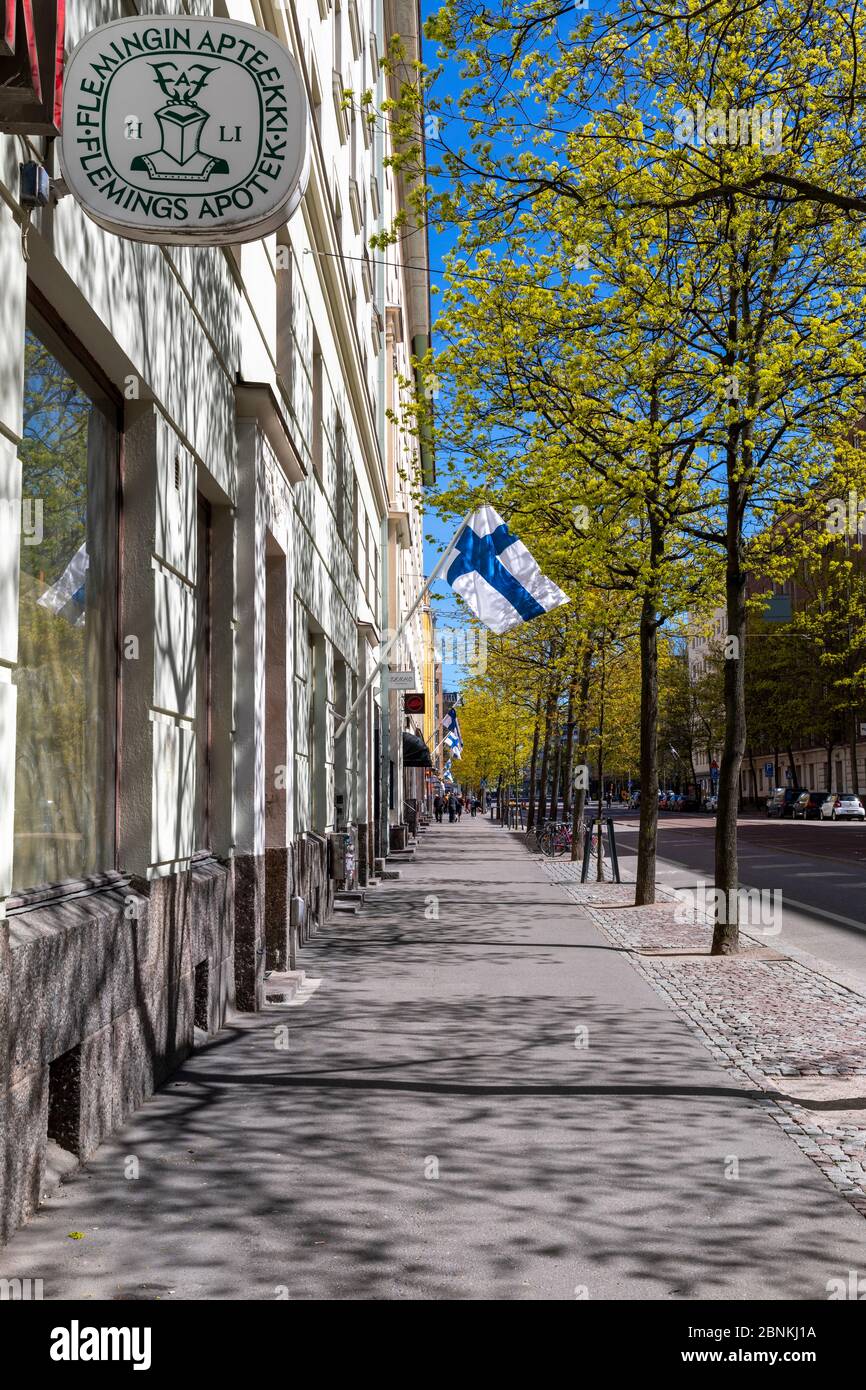 Le strade cittadine della regione di Kallio a Helsinki celebrano la Festa delle madri con bandiere finlandesi che volano sotto il sole primaverile. Foto Stock