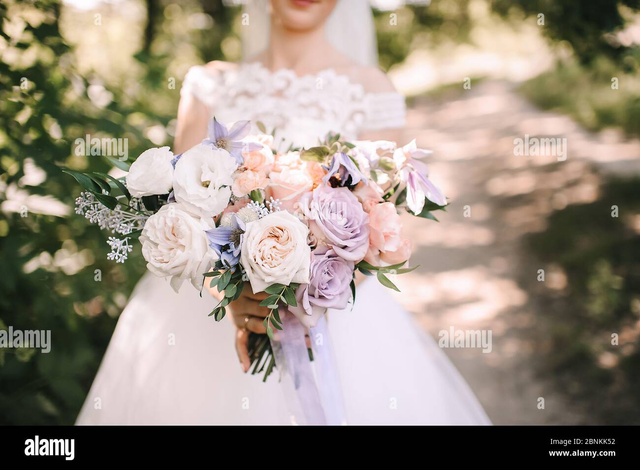 Primo piano di un bouquet di peonie, rose, garofani in tonalità bianco, rosa,  viola, lavanda. La sposa in un abito bianco pizzo contiene un bouquet i  Foto stock - Alamy