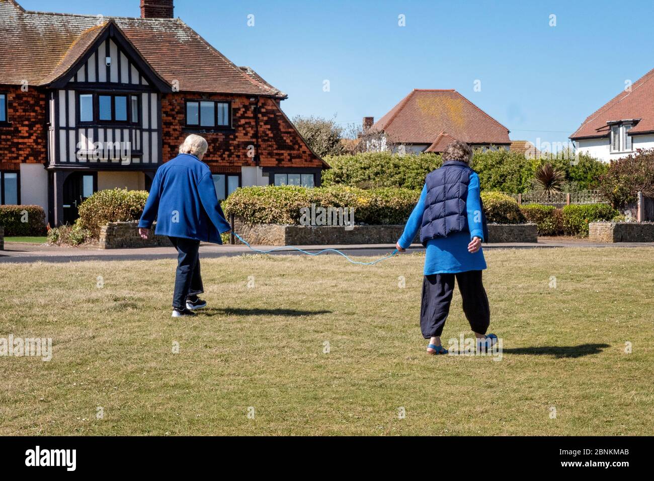 Due donne pensionati che usano una corda di 2 metri per la distanza sociale nel blocco corona-virus Foto Stock