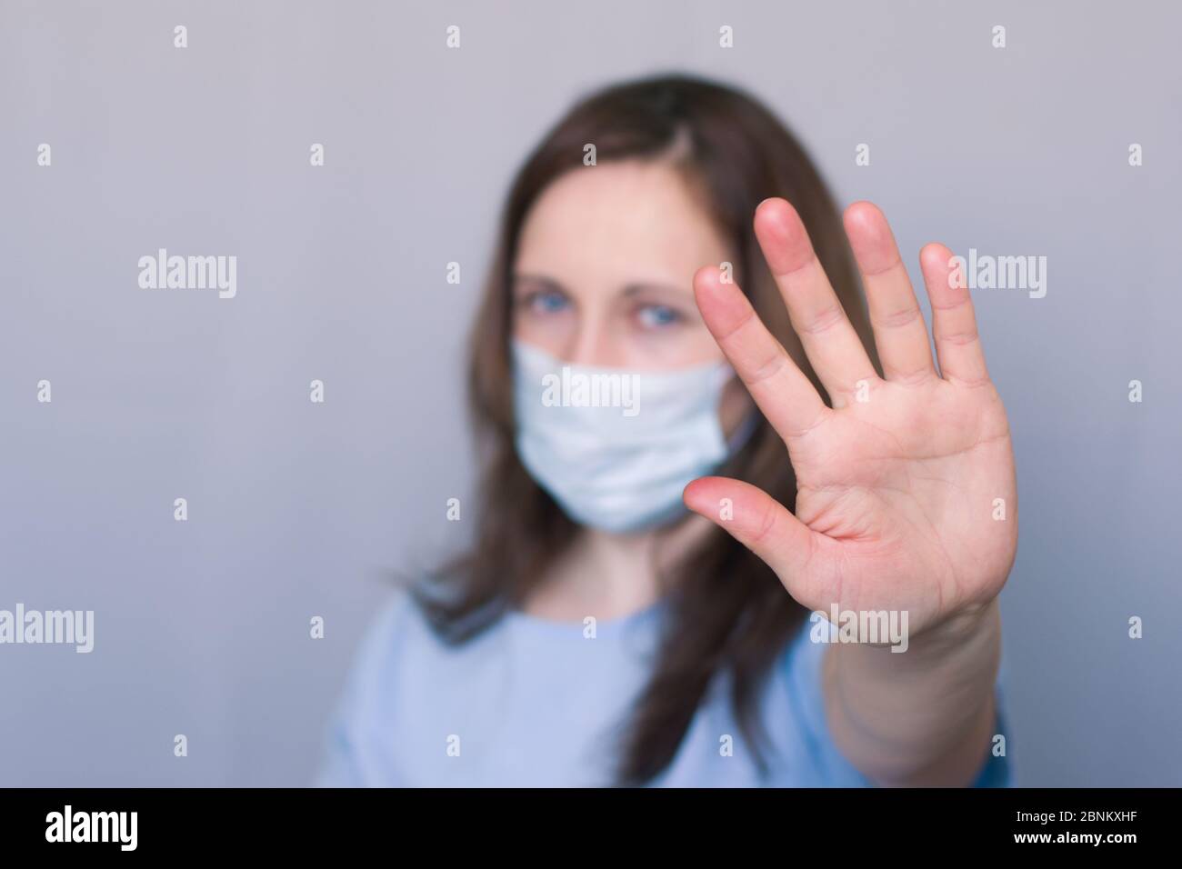 Donna in una maschera protettiva medica mostra un segnale di stop. Foto Stock