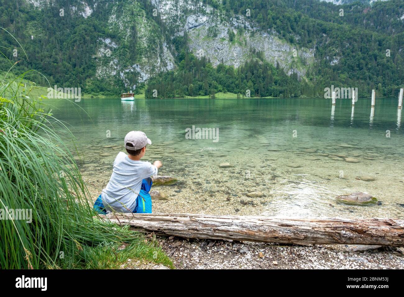 Europa, Germania, Baviera, Alpi Bavaresi, Berchtesgaden, Koenigssee, ragazzo lascia saltare le pietre a Koenigssee vicino Berchtesgaden Foto Stock