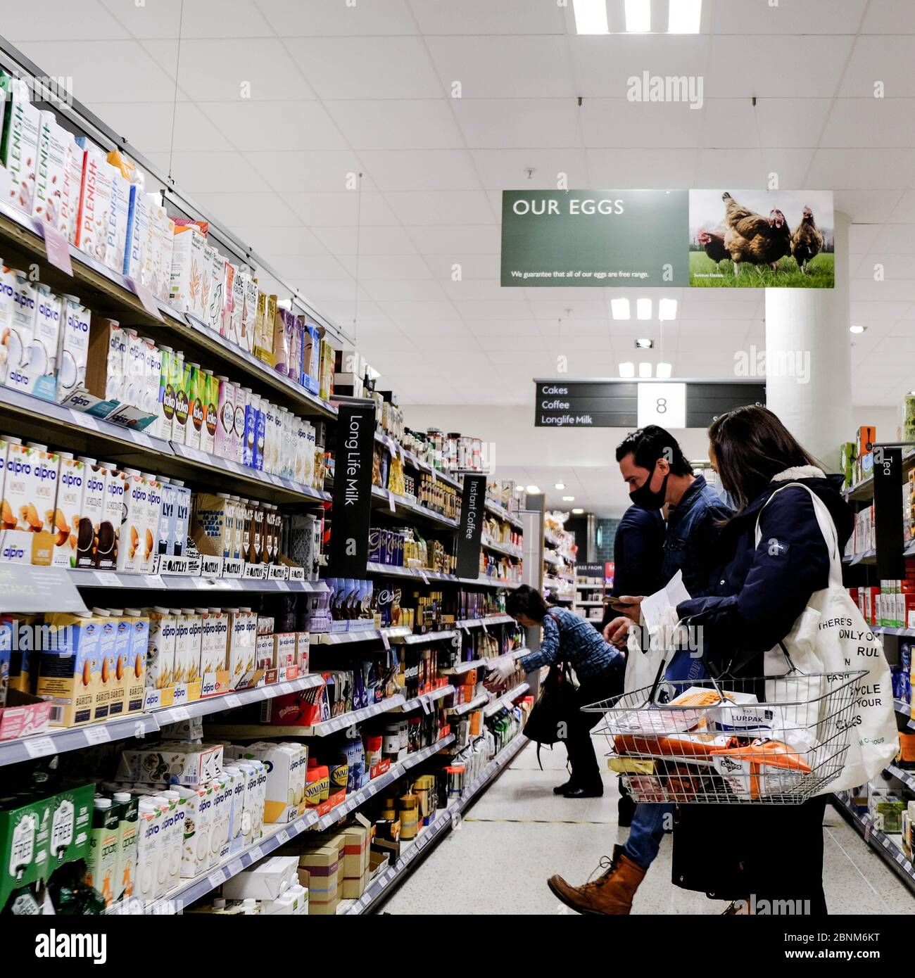 Acquirenti in un supermercato indossare maschere facciali di protezione e osservare la distanza sociale durante il Pandemic di Coronavirus Foto Stock