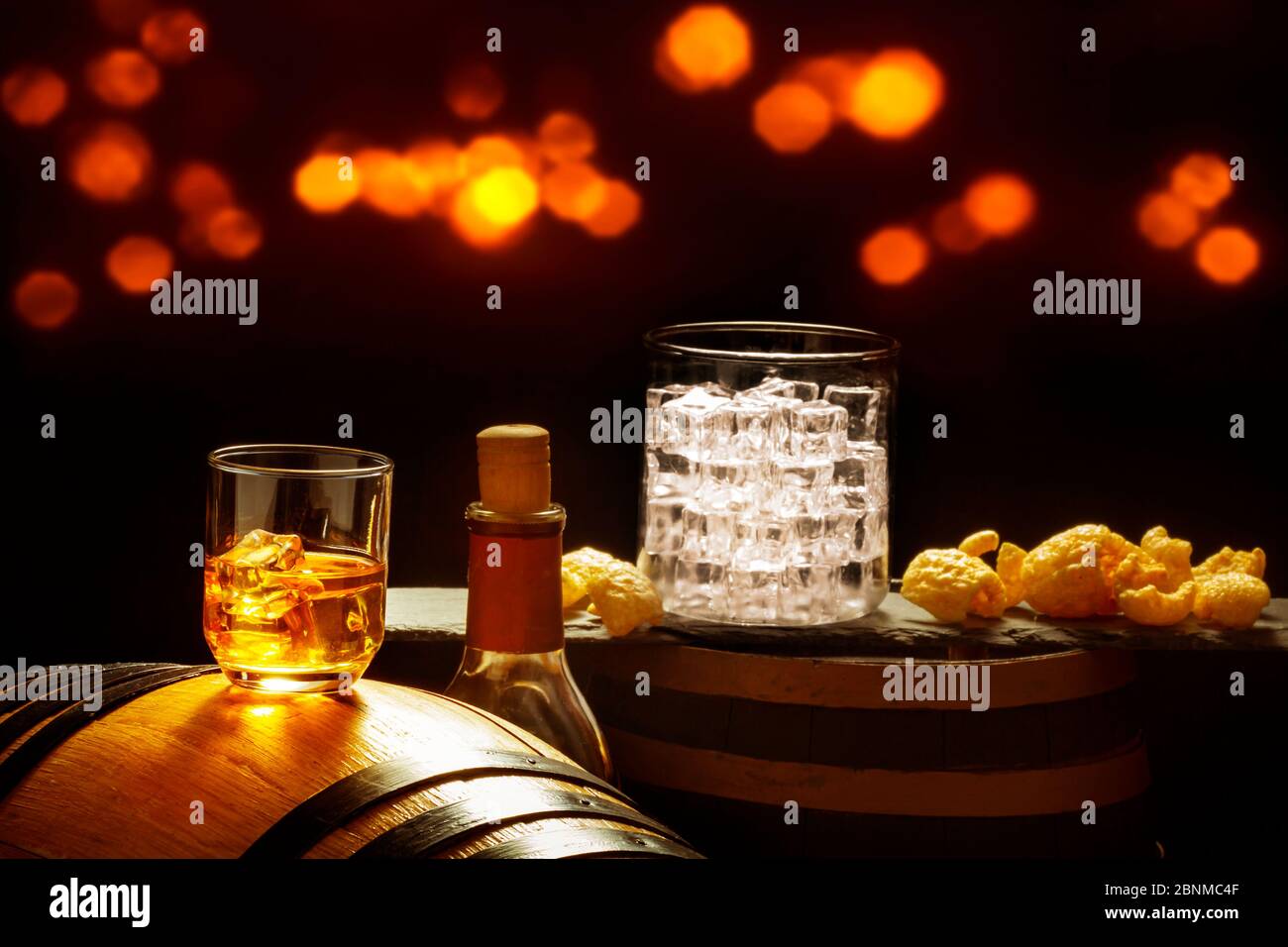 Bicchiere di whisky con cubetti di ghiaccio e patatine sui barili di whisky Foto Stock