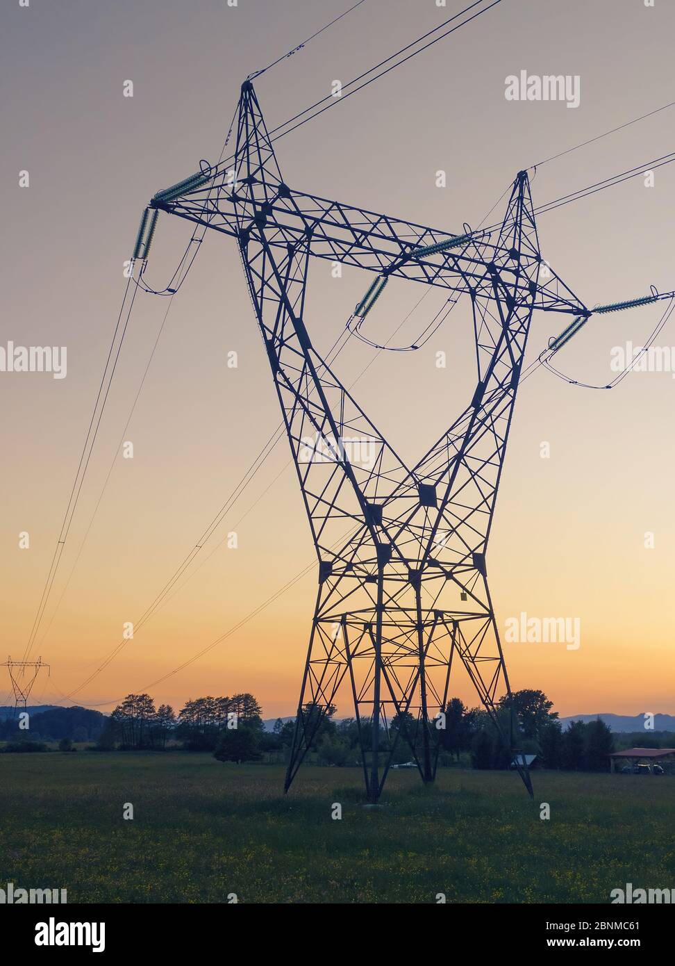 Torretta della linea elettrica di trasmissione ad alta tensione con sfondo arancione del tramonto. Elettricità, distribuzione di energia e concetti tecnologici Foto Stock