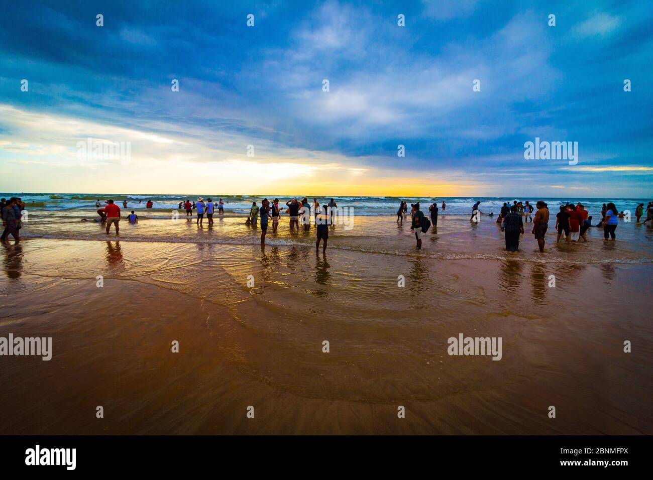 I turisti si godono la sabbia, l'oceano e il tramonto sulla spiaggia di Calangute. La più grande e senza dubbio una serie di spiagge di sabbia dorata di Goa, India. Foto Stock