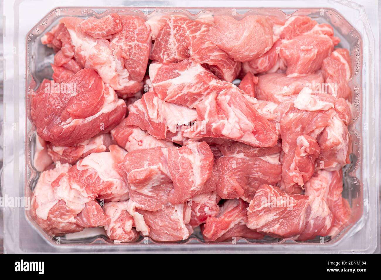 Pezzi di maiale crudo in contenitore di plastica. Fette di carne fresca, maiale dal negozio, mercato, vista dall'alto. Foto Stock