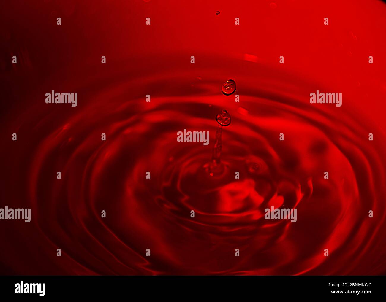 Goccia d'acqua su ciotola bianca, toni rossi, bluastro, onde, Foto Stock