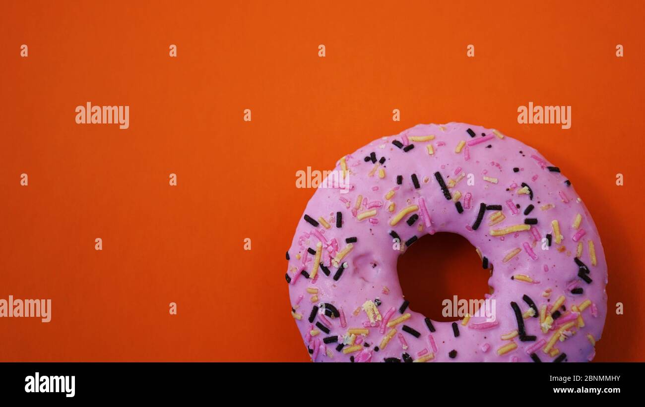Dolce ciambella rosa su sfondo arancione - posto per il testo Foto Stock