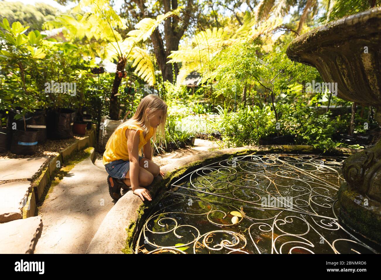 Una ragazza caucasica che esplora un giardino soleggiato Foto Stock