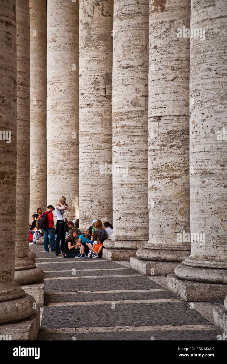 Gruppo scolastico che si rifugia dal sole nelle colonne di Piazza San Pietro a Roma Foto Stock