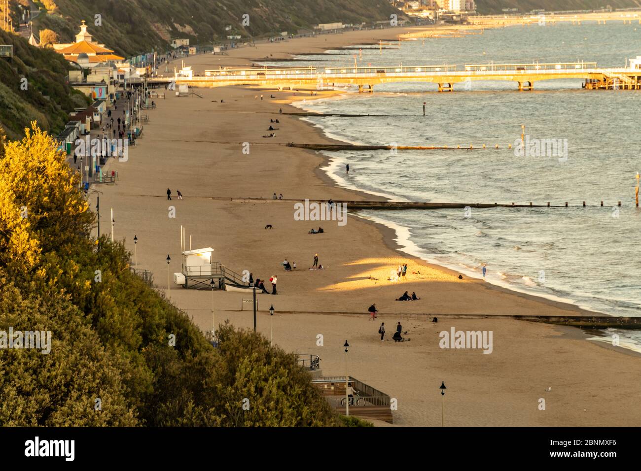 Bournemouth, Regno Unito. Venerdì 15 maggio 2020. La gente visita la spiaggia al tramonto con qualche divaricamento sociale a Bournemouth, Regno Unito. Persone a piedi e a cavallo sulla passeggiata e spiaggia di sabbia. Credit: Thomas Faull/Alamy Live News Foto Stock