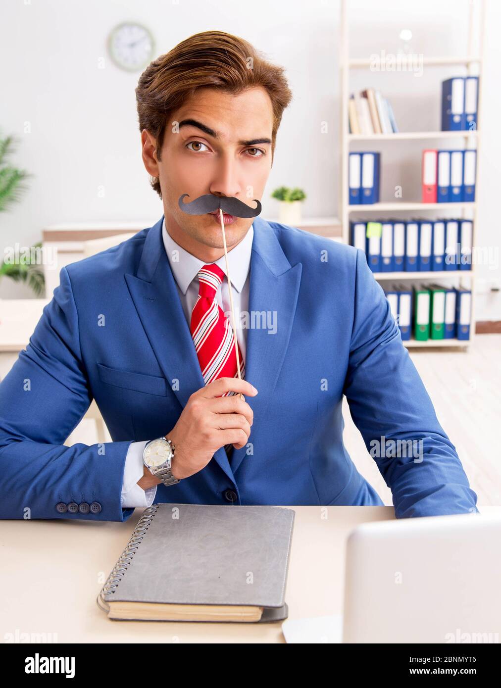 La divertente bisinessman con baffi finti in ufficio Foto Stock