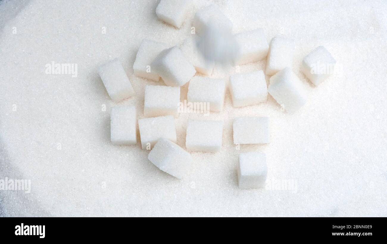 I cubetti di zucchero bianco cadono su granulato. Foto Stock