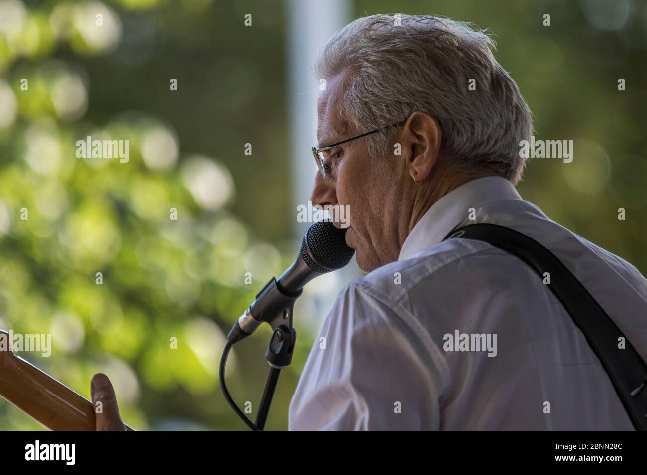 Musicista vestito, suonando un fender statocaster, cantando e in concerto all'aperto. Foto Stock