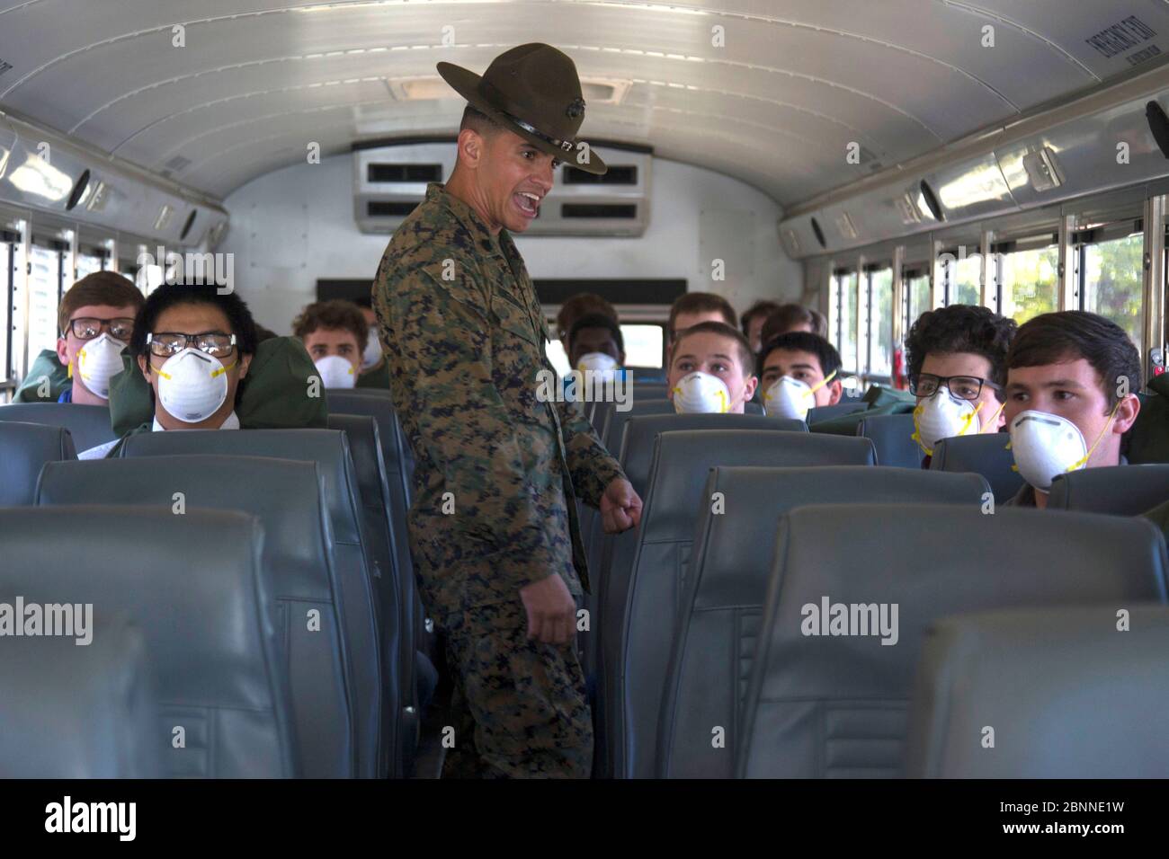 Istruttore di trapano del corpo marino degli Stati Uniti SSgt. Fernando Nunez Martinez, accoglie la maschera di protezione indossando reclute quando arrivano in autobus al Marine Corps Recruit Depot 15 maggio 2020 a San Diego, California. Foto Stock
