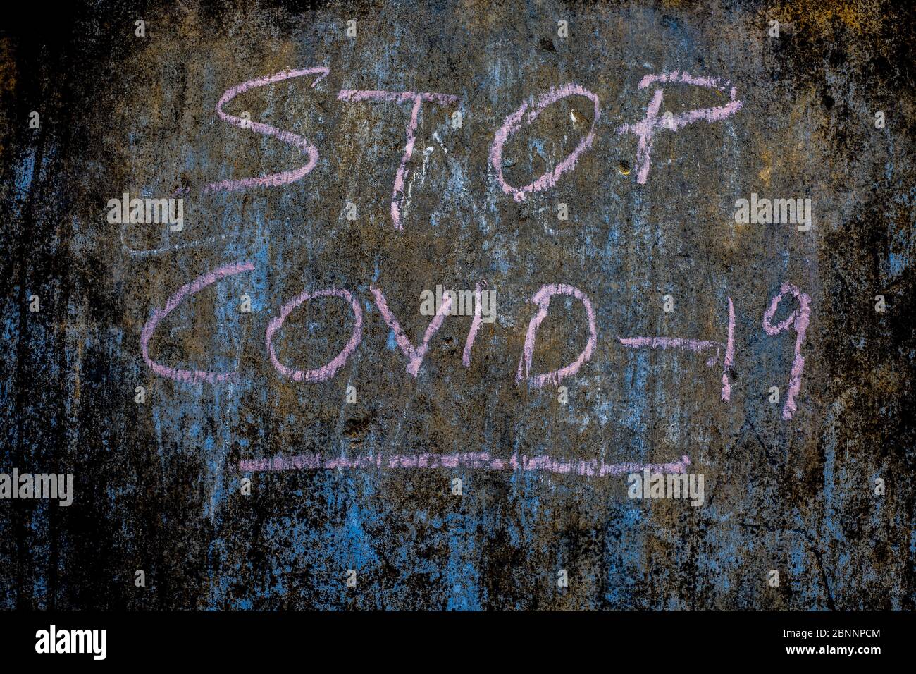 Stop COVID 19 ha scritto su una parete di tessitura ruvida con gesso rosa, colpo orizzontale. Foto Stock