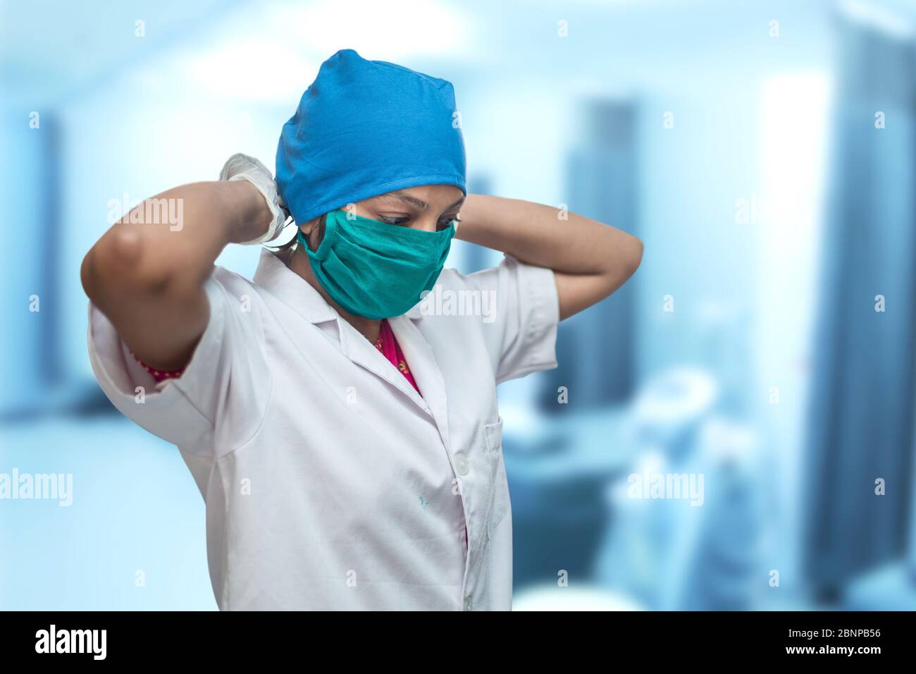 Primo piano di una lavoratrice medica femminile, infermiera che mette su una maschera chirurgica respiratore per proteggere dal coronavirus, Covid-19 Pandemic. Foto Stock
