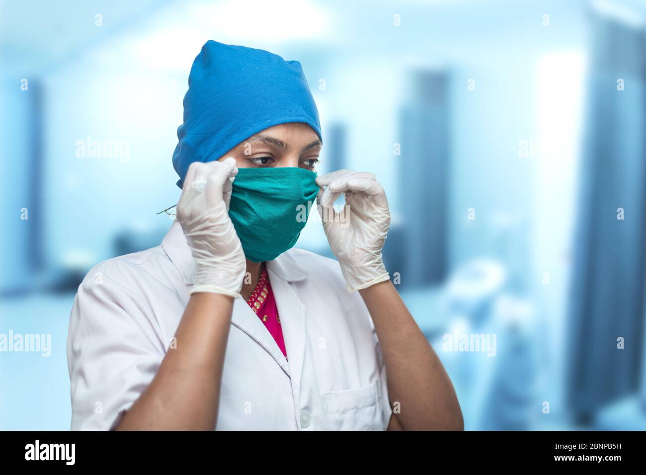 Primo piano di una lavoratrice medica femminile, infermiera che mette su una maschera chirurgica respiratore per proteggere dal coronavirus, Covid-19 Pandemic. Foto Stock