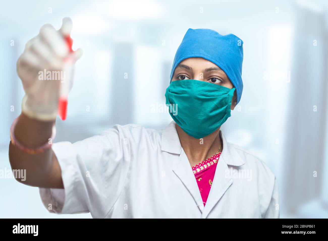 Medico, infermiere che indossa una maschera chirurgica che contiene una provetta per il test con il campione di sangue del paziente Coronavirus per lo scopo del test, Covid=19 Pandemic. Foto Stock