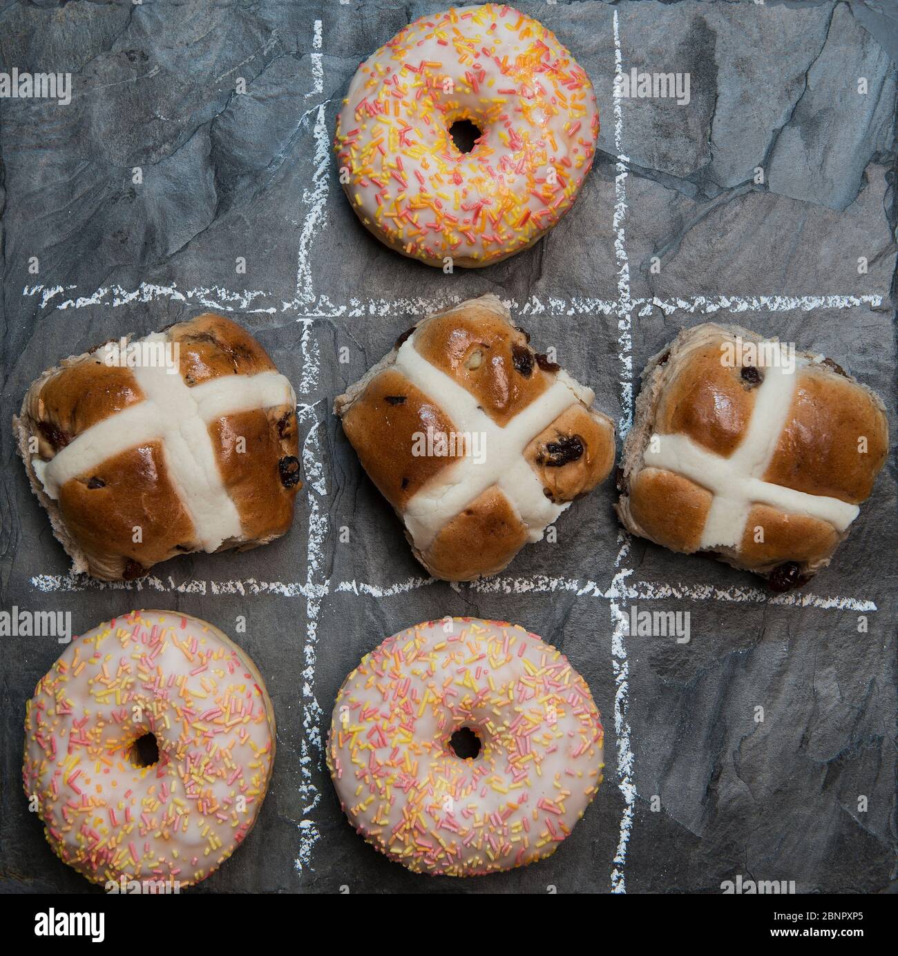 Giocando noughts e croci con ciambelle e focacce di croce calda, una di sequenza di immagini Foto Stock