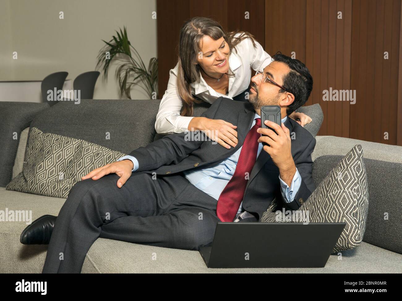Uomo arabo lavorano a casa mentre la donna è guardando sopra la sua spalla cercando di ottenere la sua attenzione Foto Stock