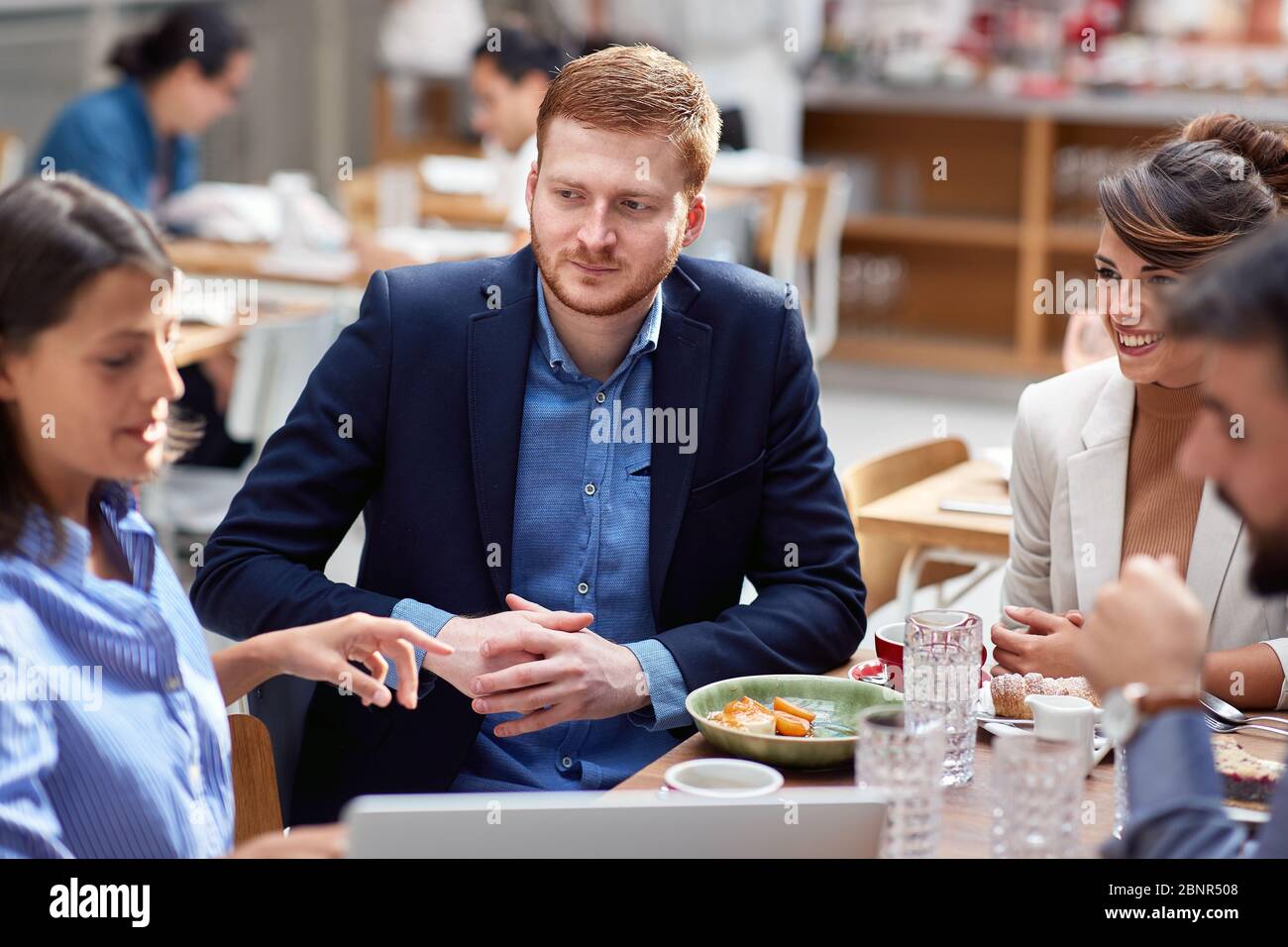 giovane bararda caucasica con i suoi amici a pranzo in ristorante. amici, colleghi, partner commerciali, pranzo, pausa Foto Stock