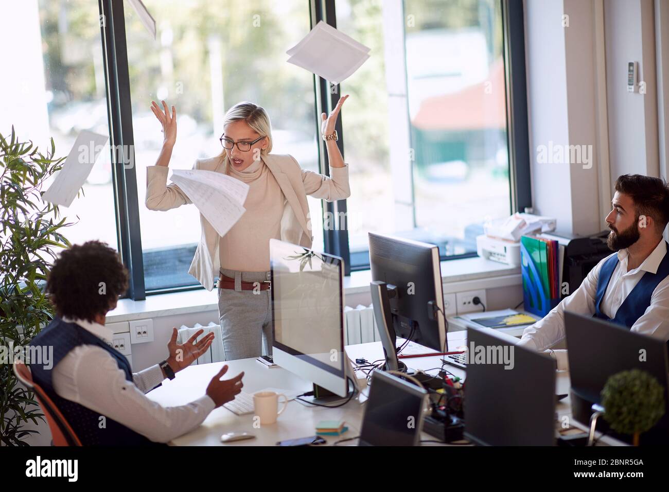 Donna d'affari che si arrabbia a un collega. Donna d'affari che getta le carte in rabbia. Ambiente ostile. Foto Stock