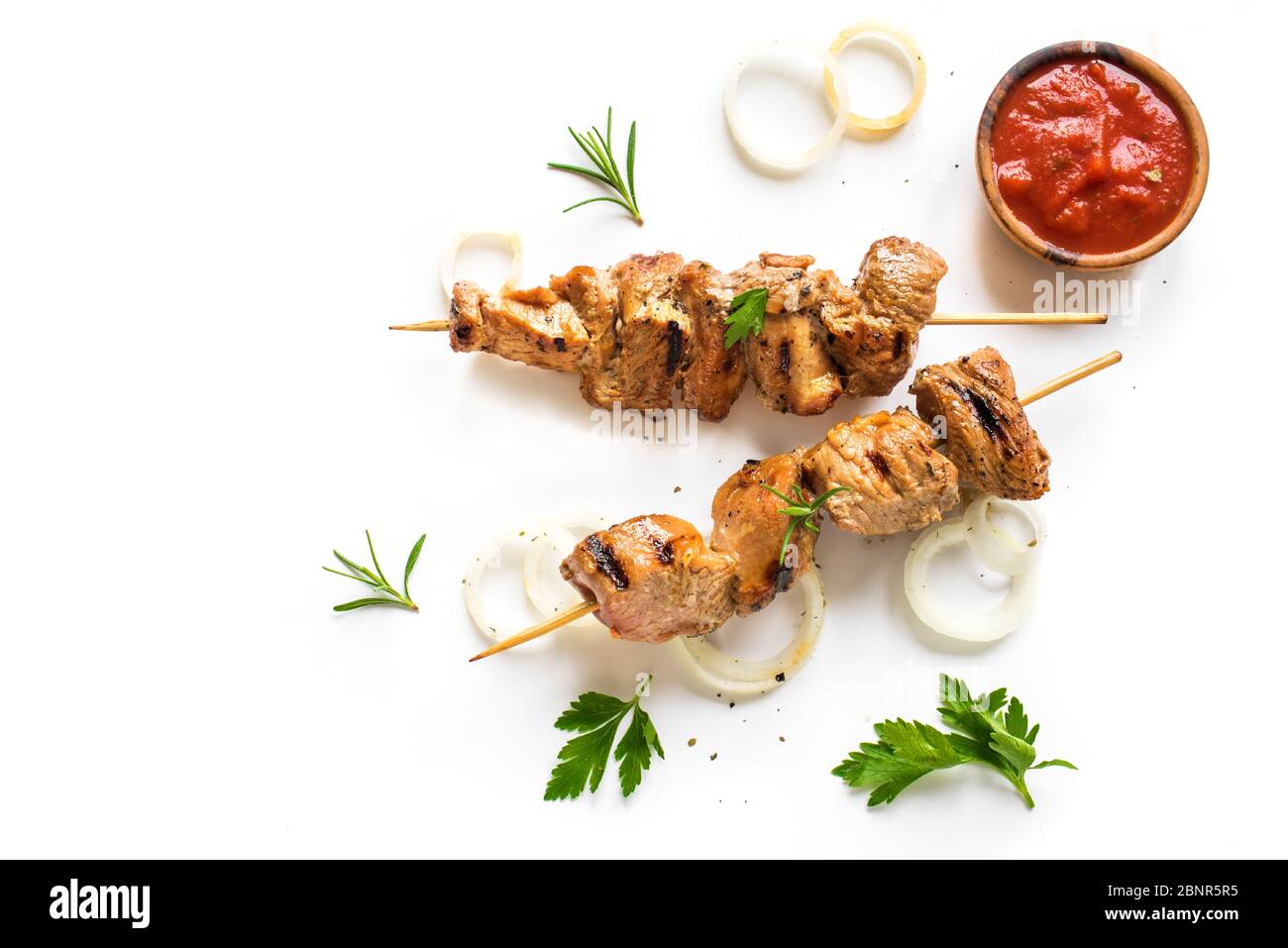 Spiedini di maiale alla griglia isolati su sfondo bianco, vista dall'alto. Carne di maiale, pollo o tacchino, shish kebab con salsa di pomodoro, erbe e spezie. Foto Stock