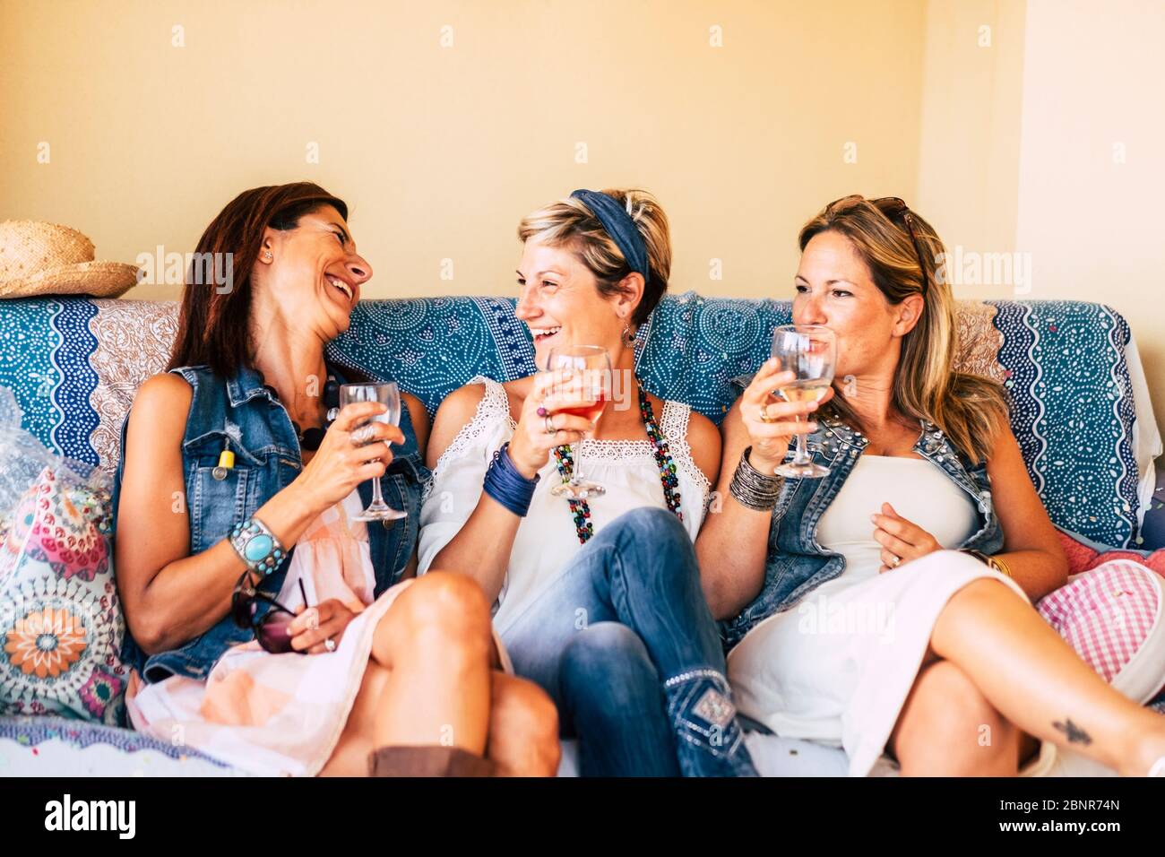 Gruppo di giovani donne adulte di mezza età che si divertono insieme a tostare e a sorseggiare bicchieri di vino sulla spiaggia durante un tramonto dorato godendo di attività ricreative all'aperto o di una vacanza Foto Stock
