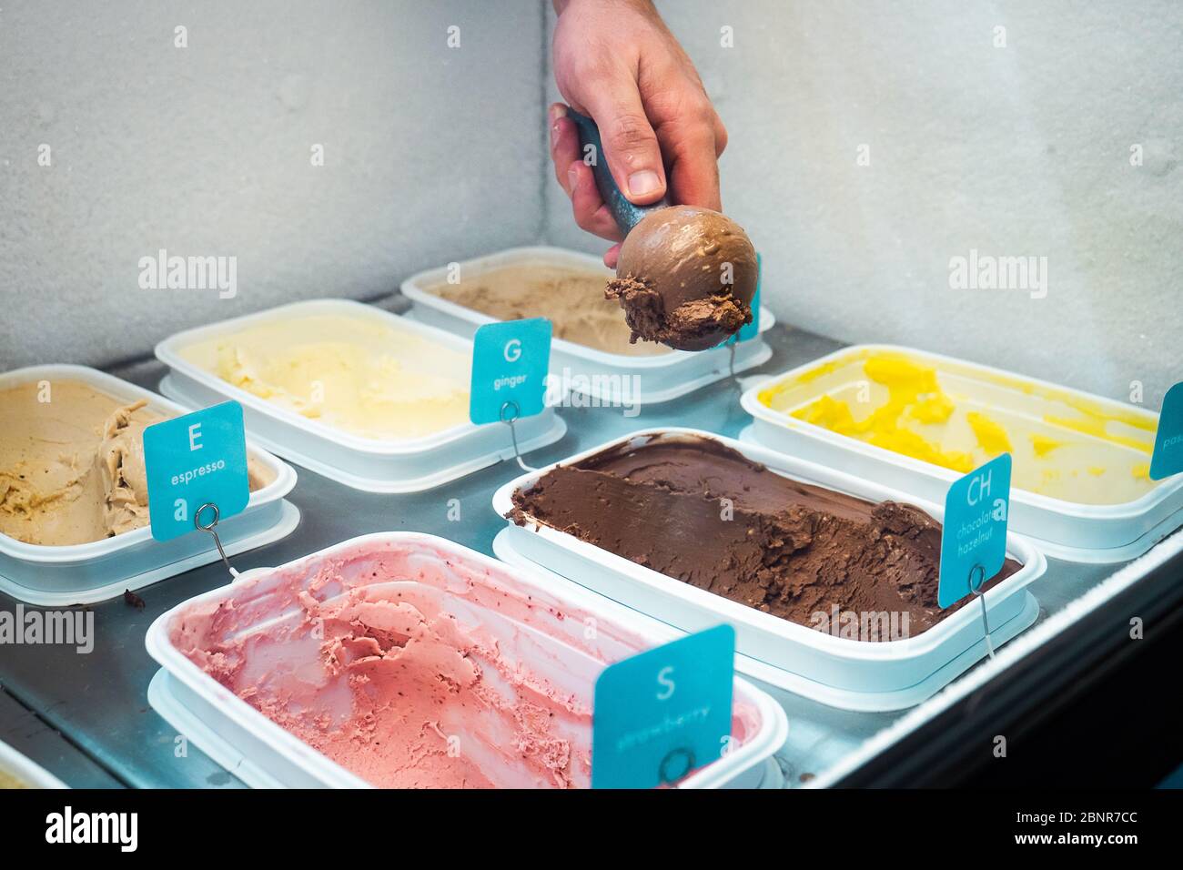 Uomo mano che scopano gelato al cioccolato in una gelateria Foto Stock