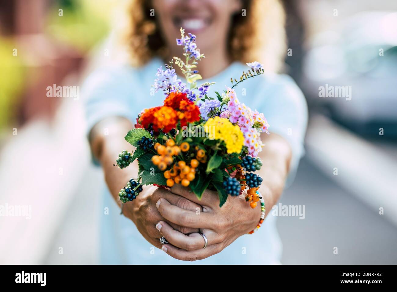 Primo piano di fiori freschi di colore bouquet in primo piano e felice donna allegro in background - mercato di nozze e fiori natura Foto Stock