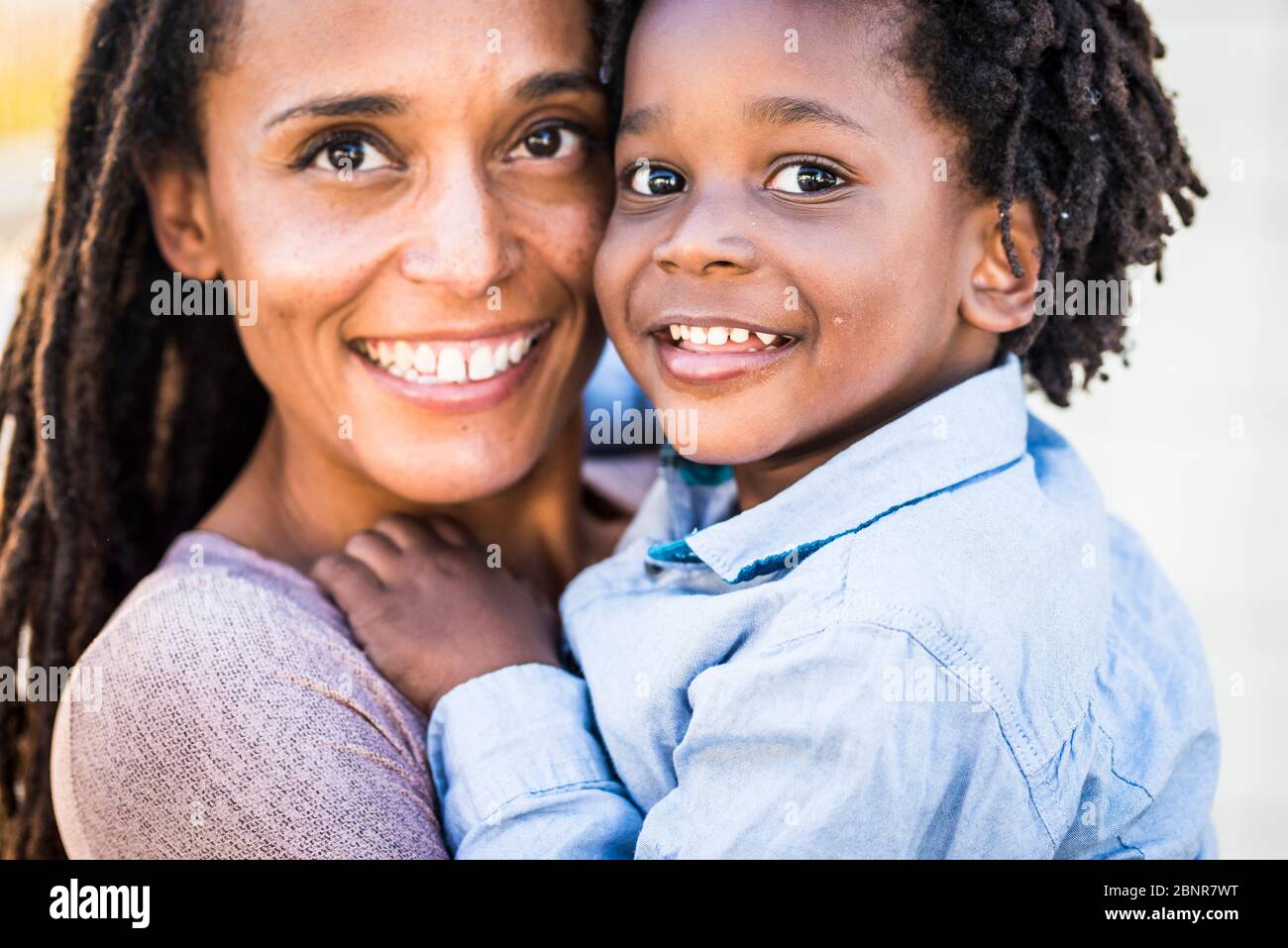 Ritratto di famiglia coppia madre e figlio nero afro razza etnica sorriso e guardare la fotocamera - concetto di diversità e mamma single con bambini piccoli - felicità e gioia concetto con amore - concentrarsi sugli occhi dei bambini Foto Stock