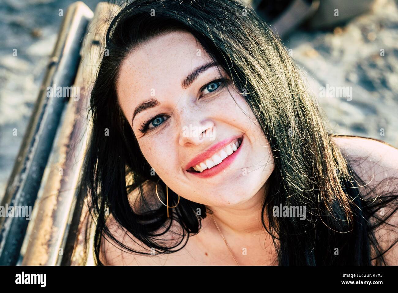 Bella giovane donna caucasica ritratto sorriso alla macchina fotografica - allegro felice gente con occhi blu e lunghi capelli neri in attività di svago all'aperto da solo Foto Stock