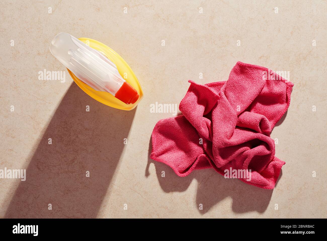 Detergente o detergente in una bottiglia spray e un panno rosa per la pulizia sulla superficie in marmo. Disinfezione e pulizia domestica. Foto Stock