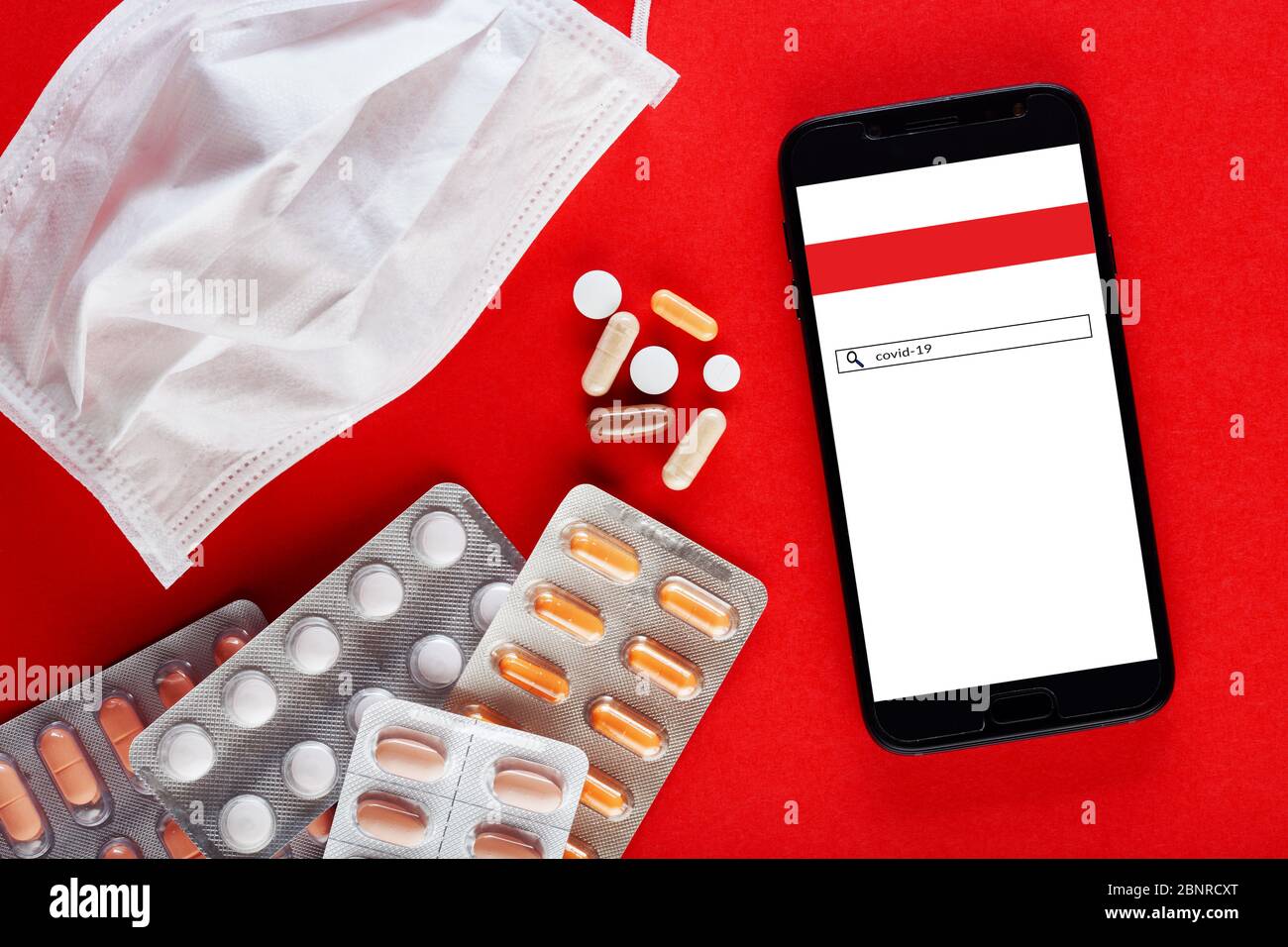 Maschera medica, pillole e telefono cellulare con informazioni sul virus corona o covid-19. Trattamento domestico o concetto di auto-cura. Foto Stock