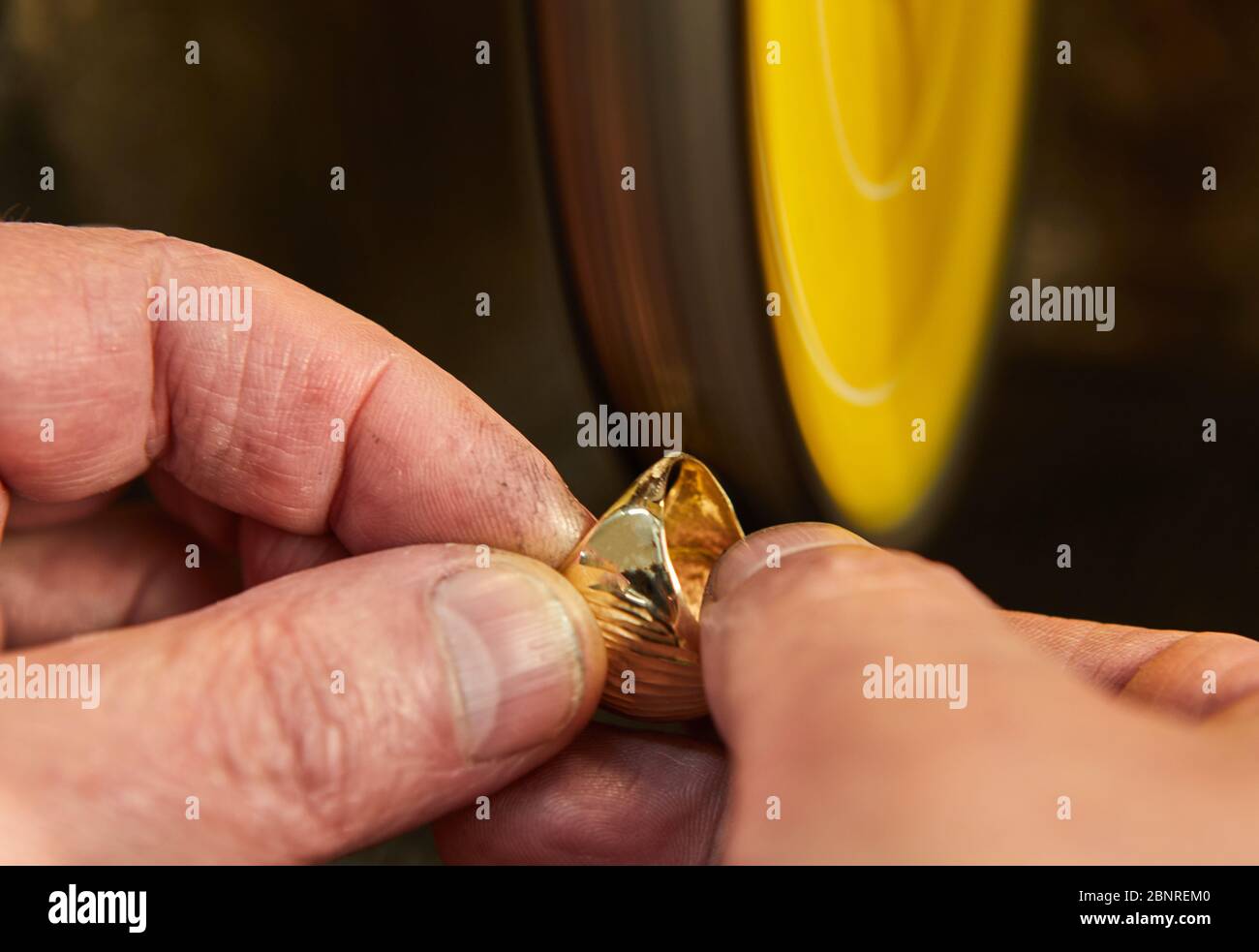 Produzione di gioielli. Gioielleria lucida un anello d'oro su una levigatrice in un laboratorio di gioielli. Foto Stock