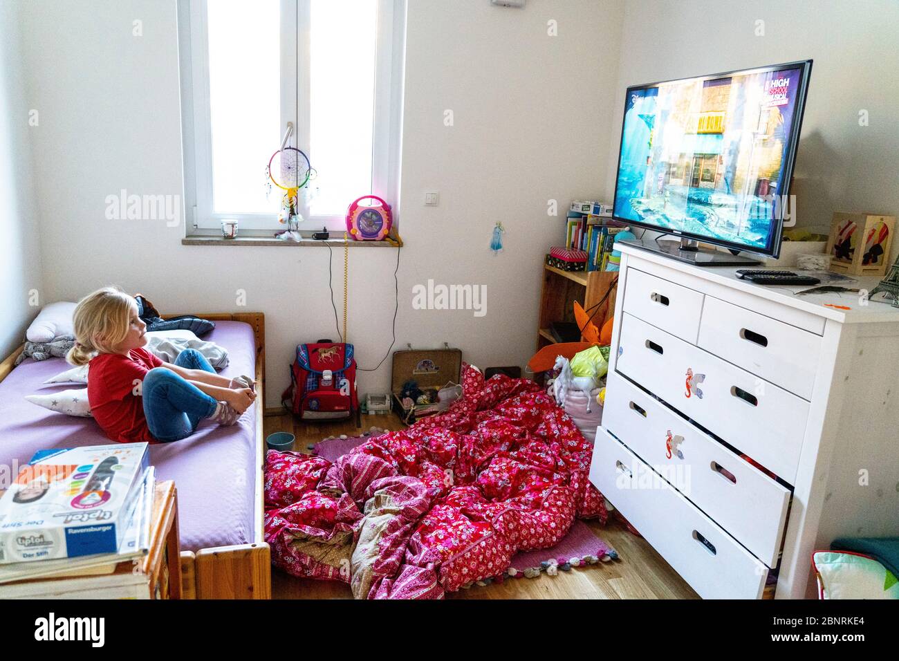 Il bambino si siede da solo davanti alla televisione nella camera dei bambini Foto Stock