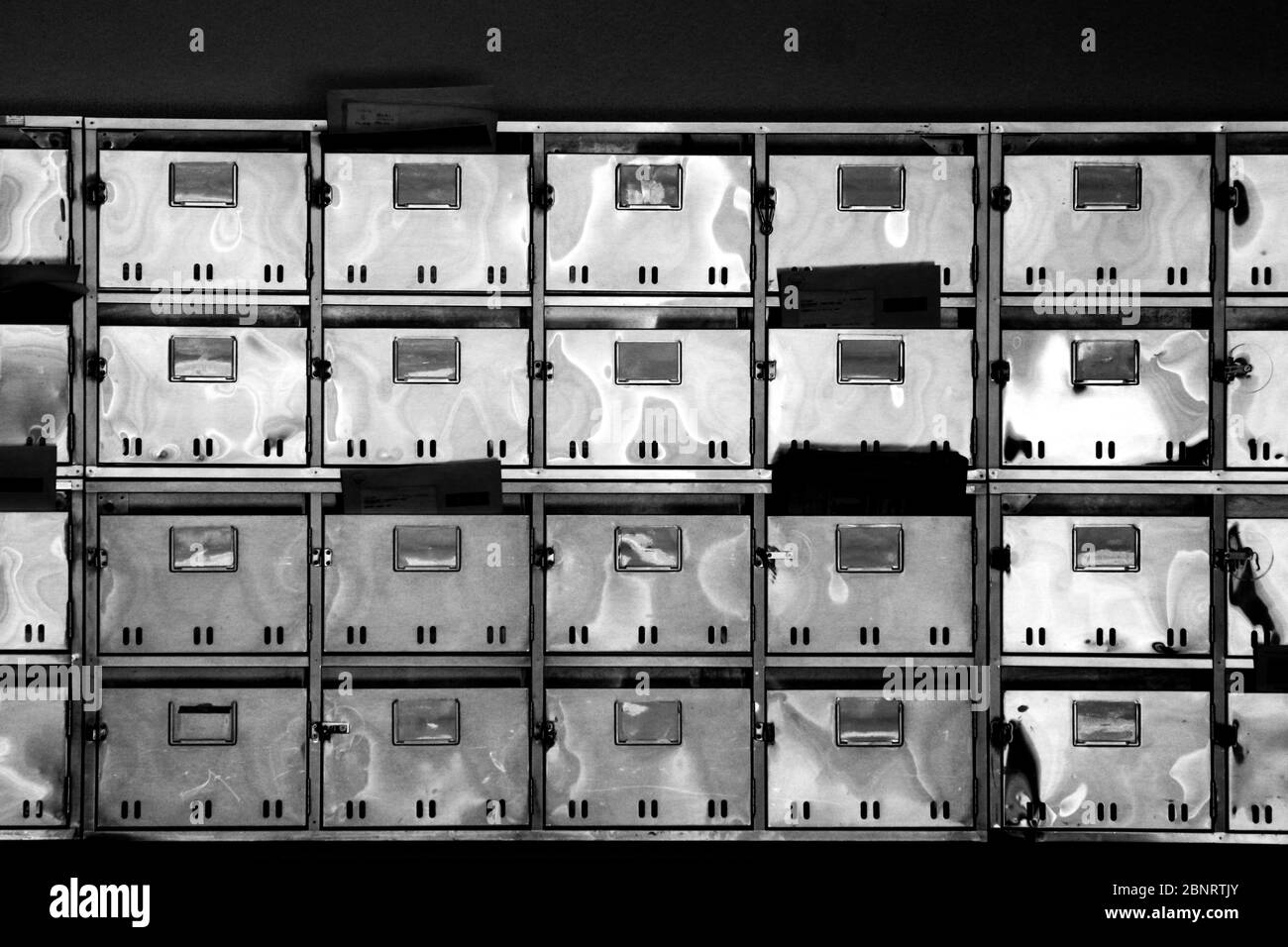 Cassette postali in acciaio inossidabile allineate all'ingresso posteriore di un vecchio edificio polivalente in Giappone Foto Stock