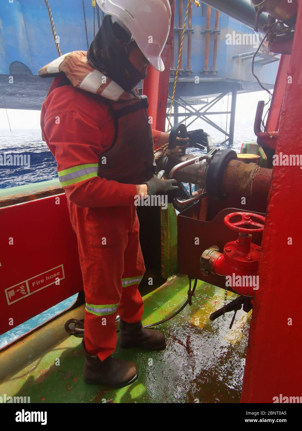 L'equipaggio marino ha scollegato il tubo flessibile del carico sul pianale indossando i DPI corretti Foto Stock