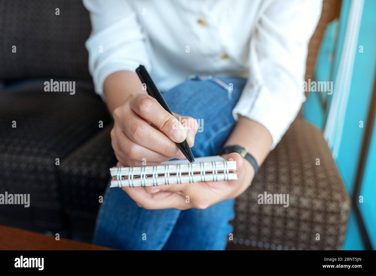Immagine closeup di una donna che tiene e scrive su un notebook vuoto Foto Stock